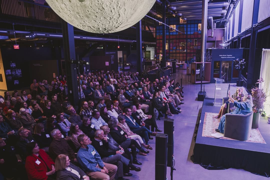 Holland Talks attendees facing a small stage inside the Luminarium, beneath a large hanging model of the moon. Image Credit: @bensemisch, Kiewit Luminarium Instagram.