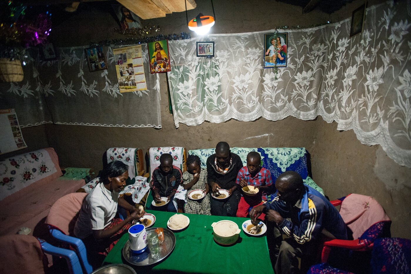 3. Alice Wafula - Alice Wafula's family eats dinner together in Khachonge, Kenya under the light provided by a solar lamp Photographer: Hailey Tucker