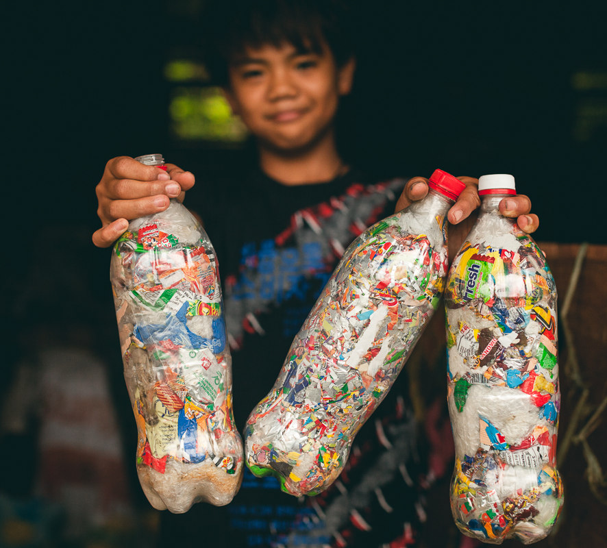 A student in Bontoc, Northern Philippines proudly holds his Ecobricks. Image Credit: Josephine Chan and Ian Christie, Wiki Commons.