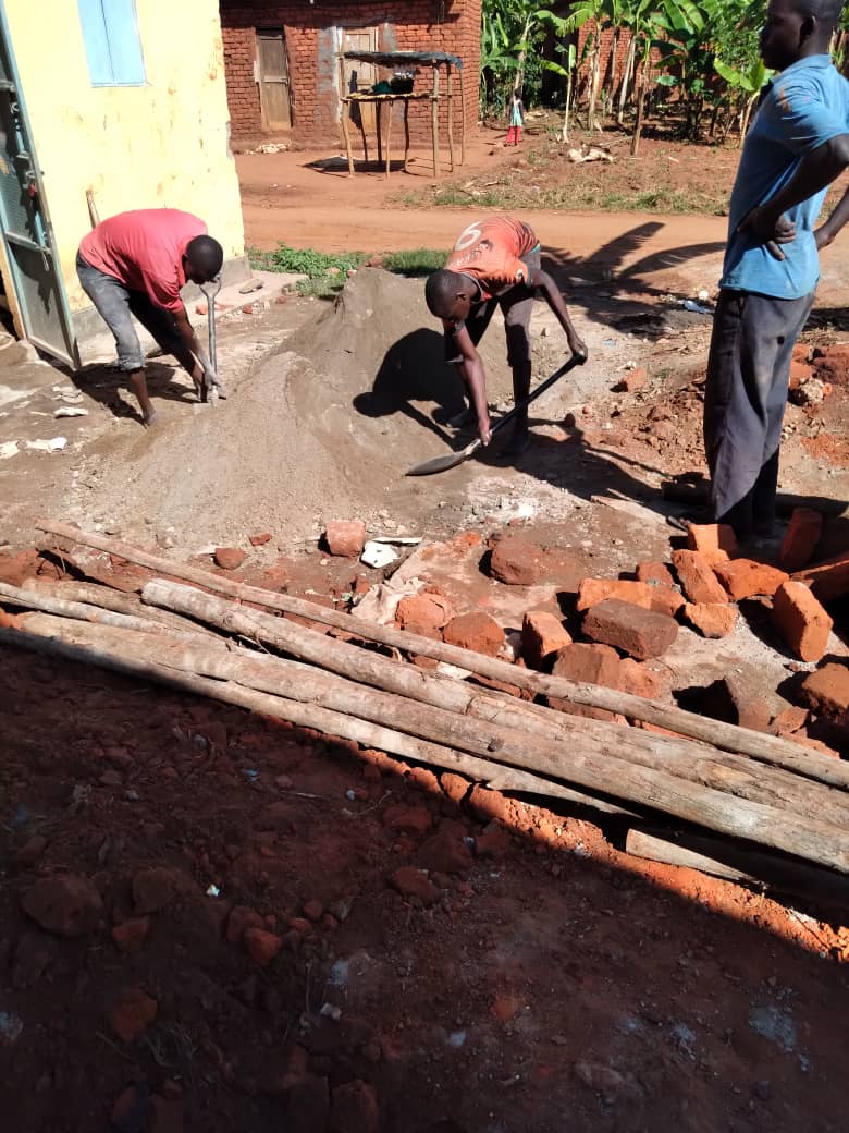 Mukhwana and his team mixing material for the construction of a new biogas pit at a rural home in Mbale district.