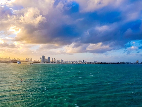 a shot of the ocean with miami skyline in the far background
