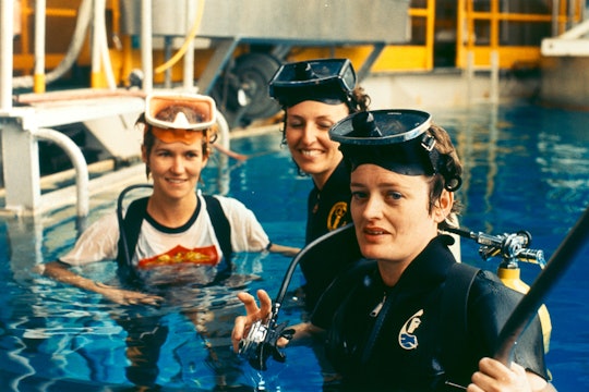 Three scientists stand in a pool with goggles and snorkels. 