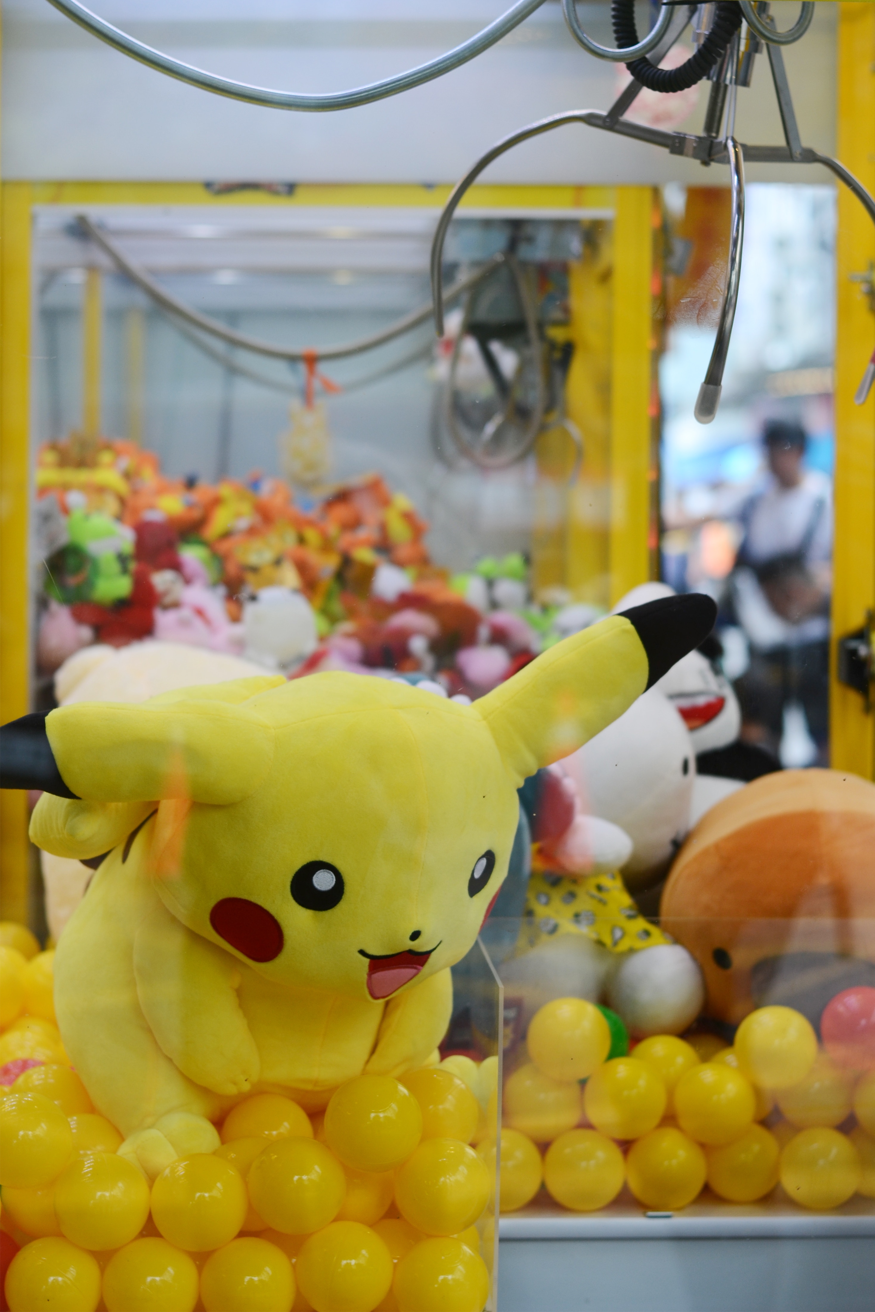 A claw machine with full of toys including a large pikachu from the Pokemon series