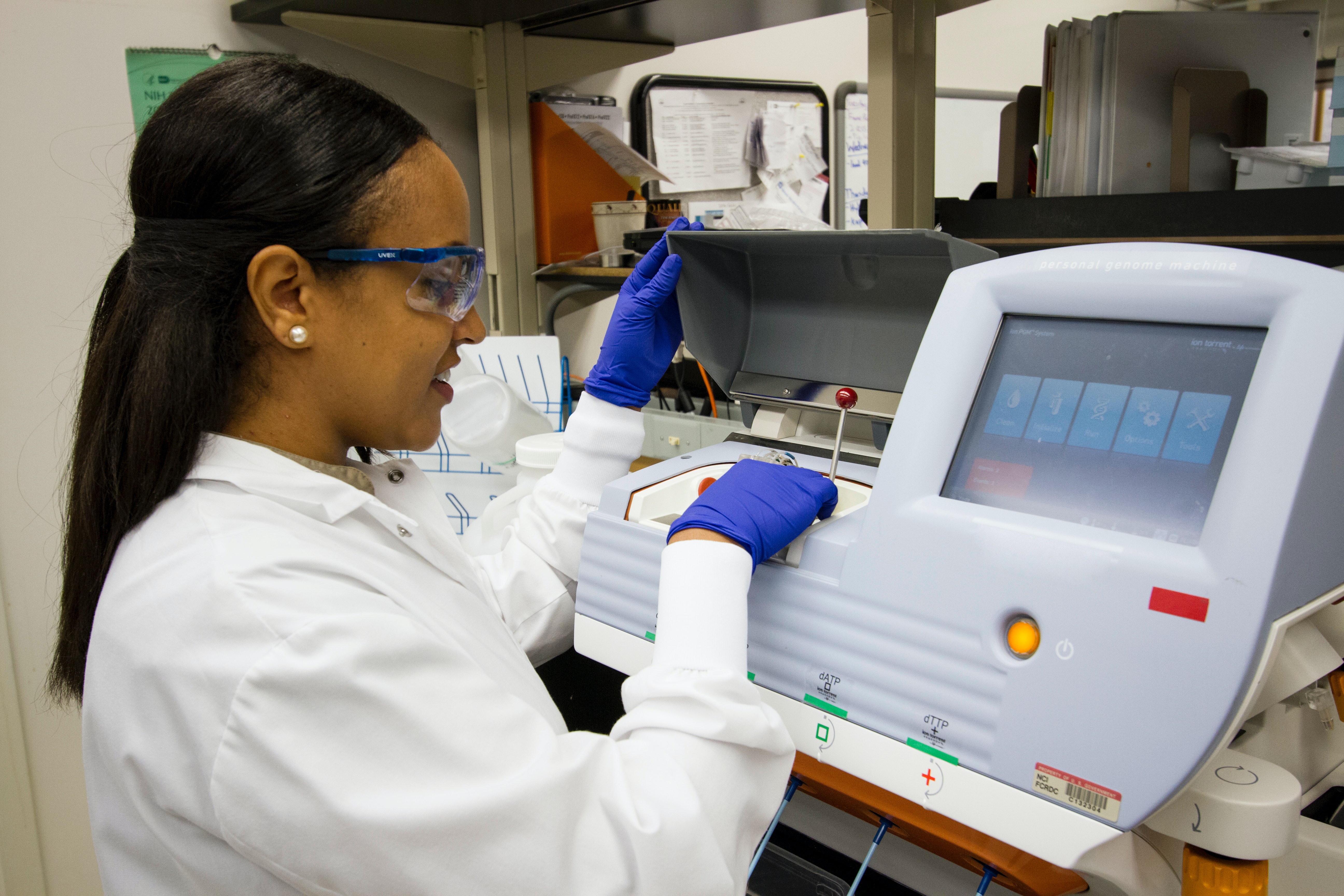 A technician loads DNA samples into a desktop genomic sequencing machine.