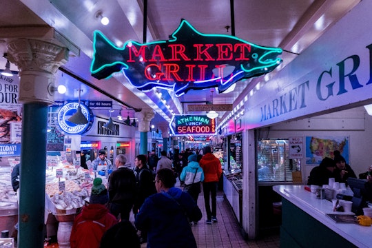 A crowd of people at the Seattle Public Market, in front of a sign that says "Market Grill."