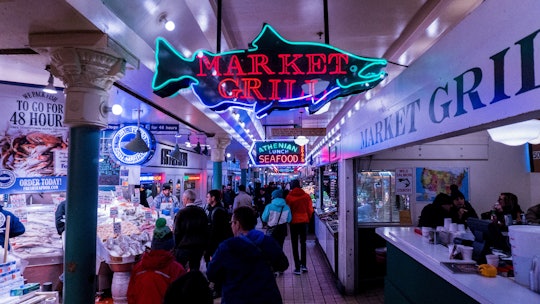 A crowd of people at the Seattle Public Market, in front of a sign that says "Market Grill."