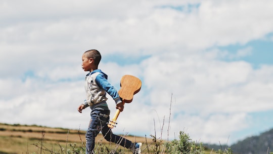 A boy walking with a ukulele. 