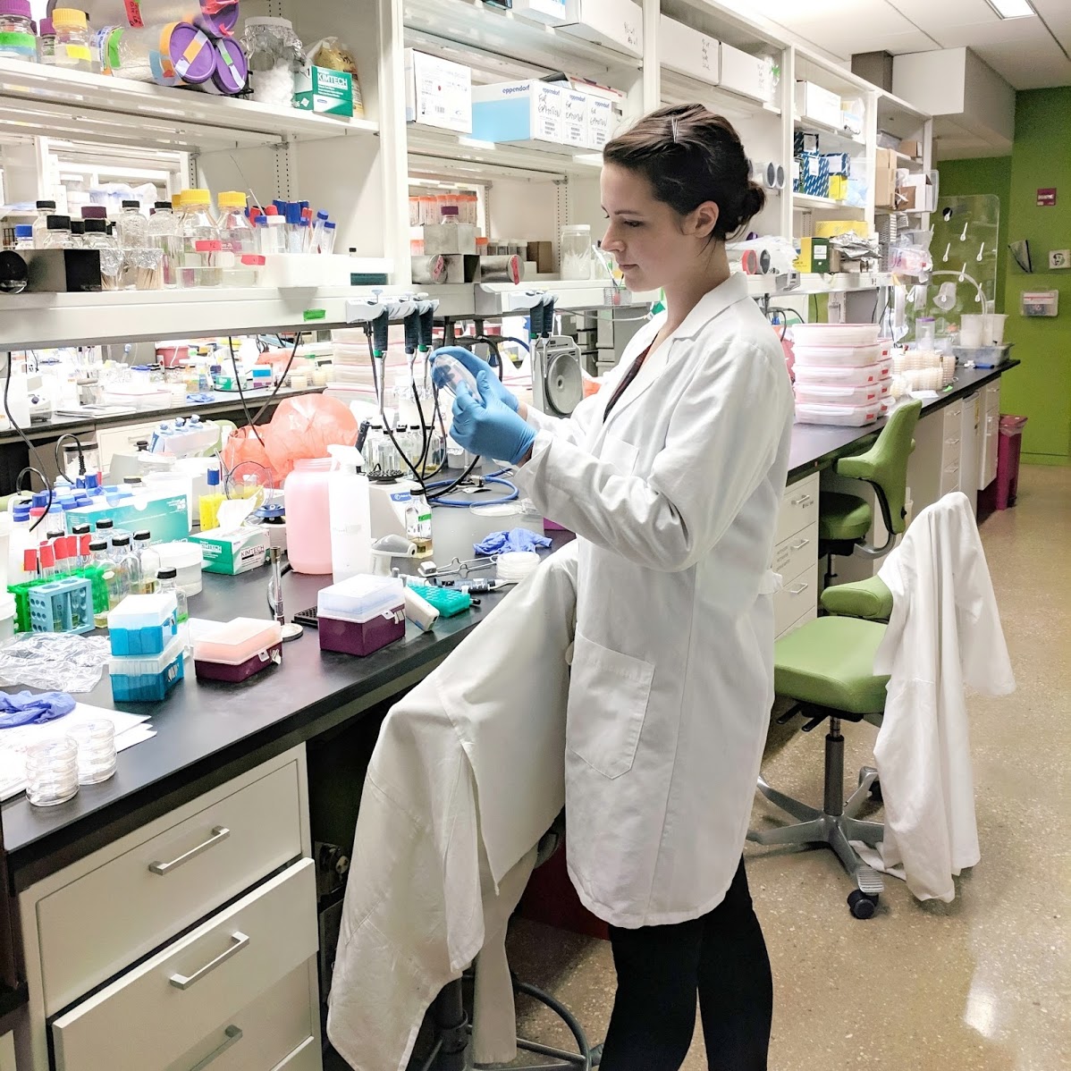 Susanna Harris working in a lab with a lab coat and blue gloves