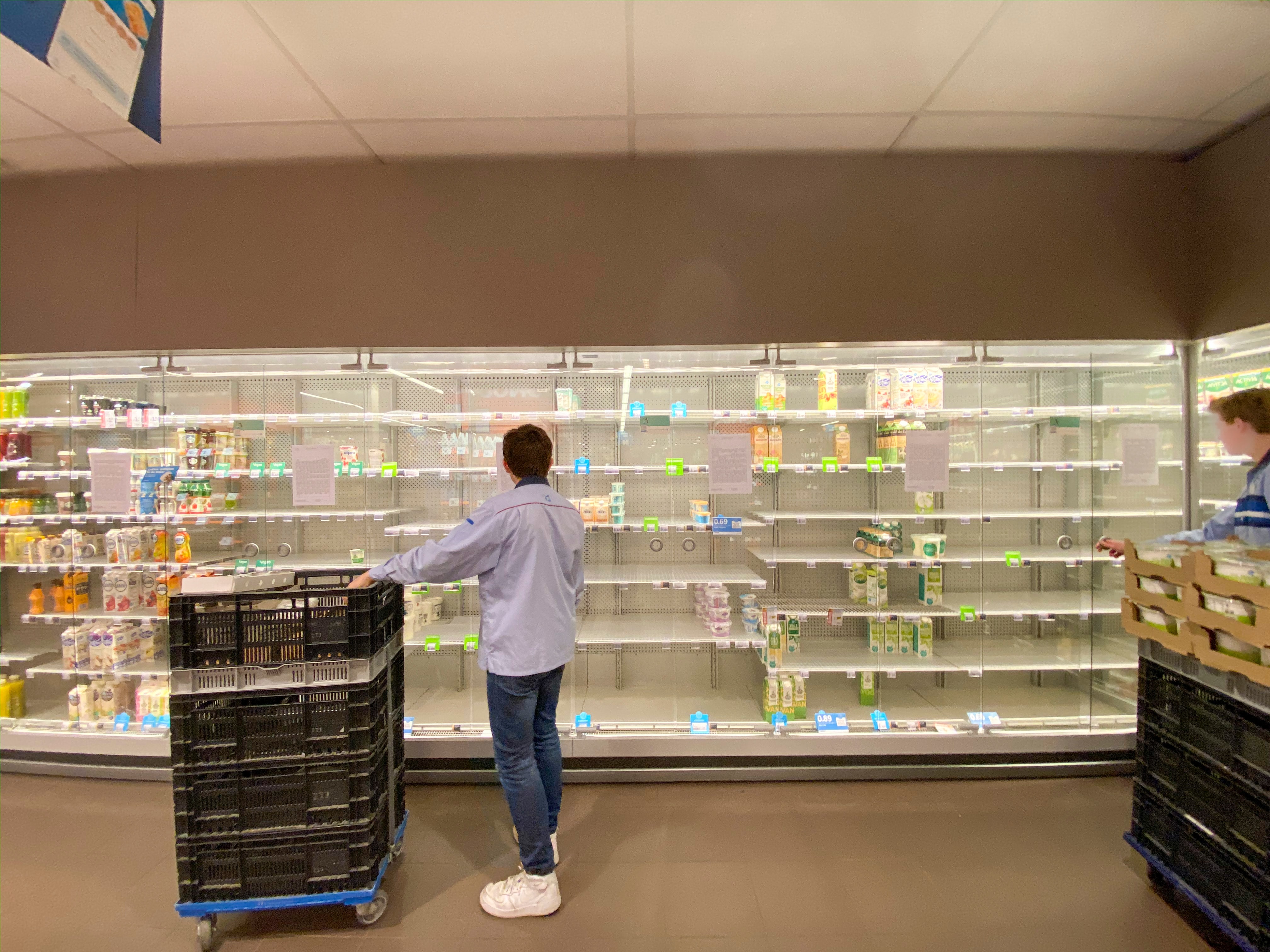 A man looking at the near empty shelves of a pharmacy 