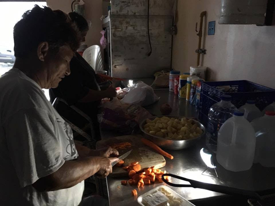 A older woman prepares dinner in a dark kitchen in Puerto Rico.