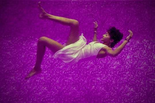 a woman wearing a white dress who looks to be dreaming, against a purple background
