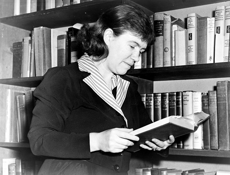 black and white photo of mead reading a book in her office