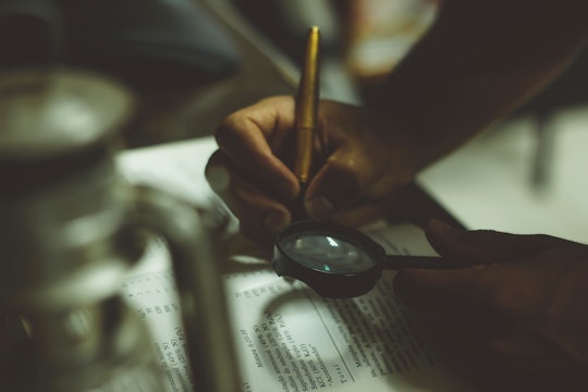 A person holding a magnifying glass to a book.