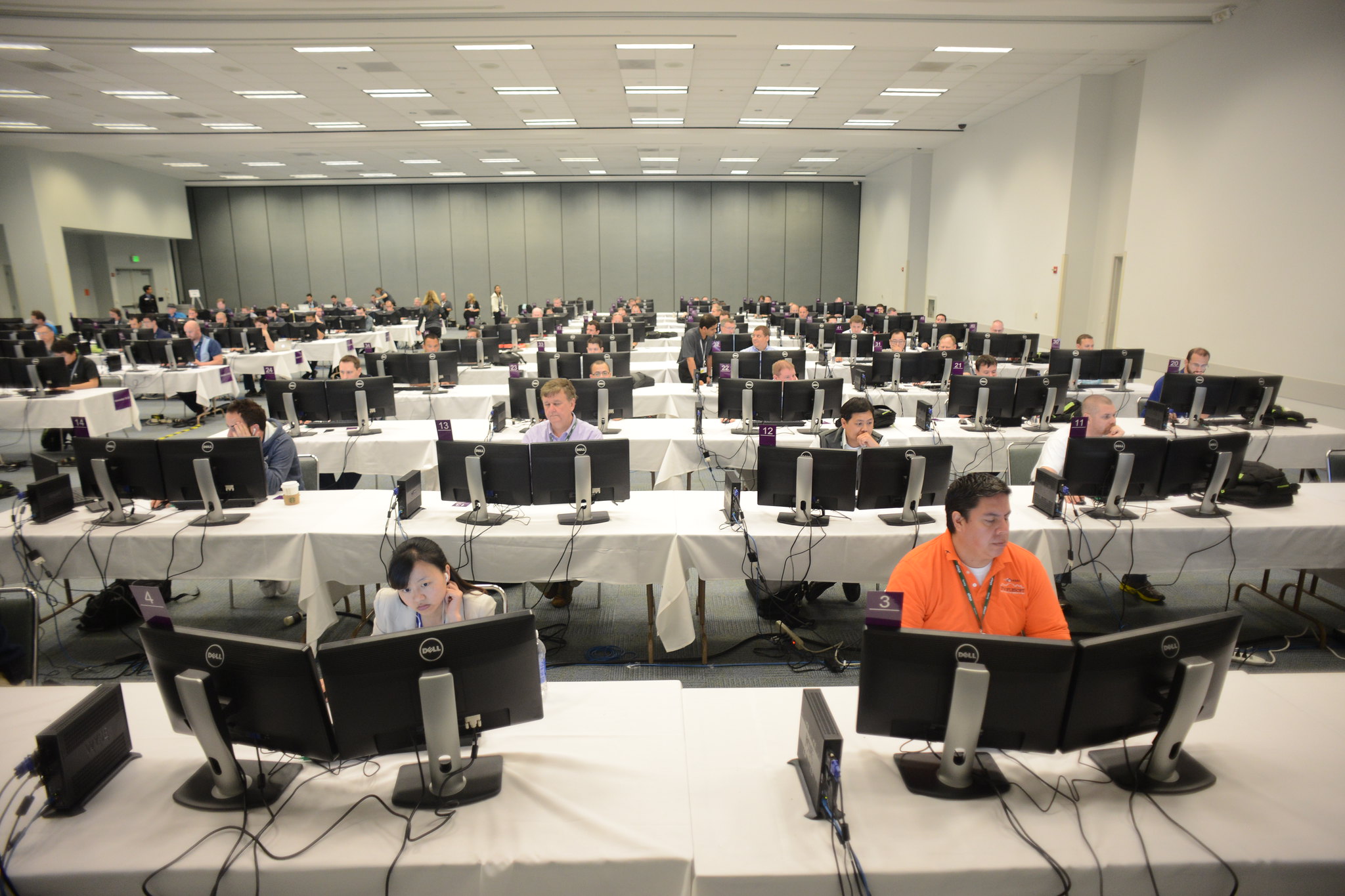 A computer lab filled with computers, with people sitting at them working.
