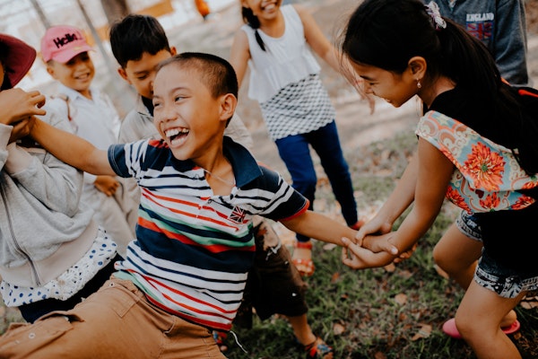 a group of kids playing outside, a happy boy is in the foreground