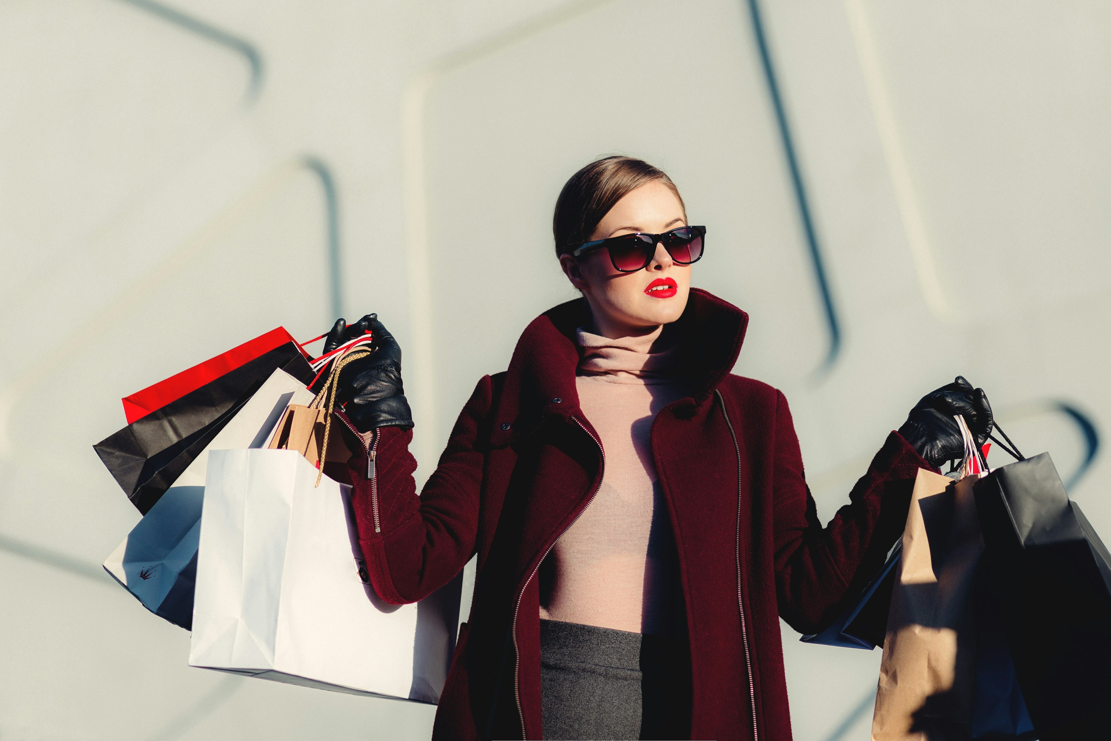 A woman wearing sunglasses holding a bunch of shopping bags.