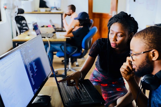 a woman teaching a man something on the computer