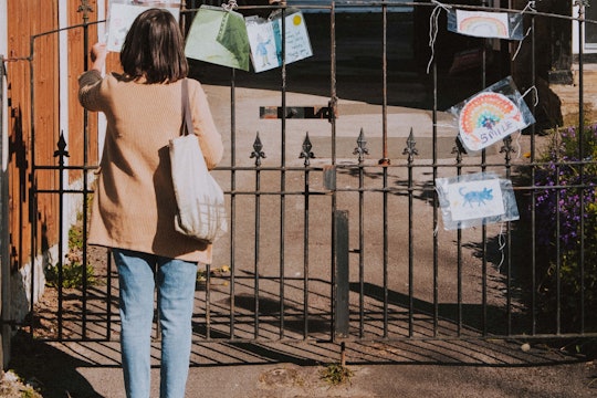 woman standing outside reading cards hanging from a gate