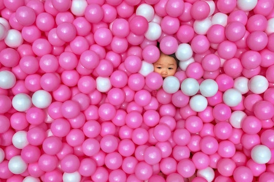 Kid in a plastic ball pen with only their face showing Kid in a plastic ball pen with only their face showing