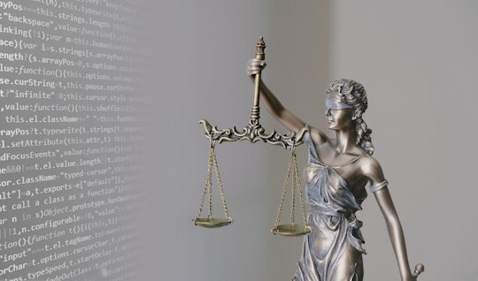 Figurine of "blind justice" with computer code in the background