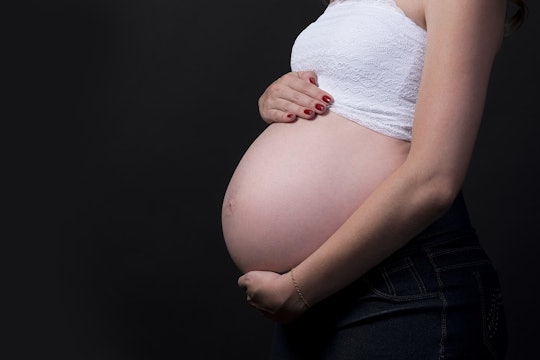 pregnant woman standing against a black background