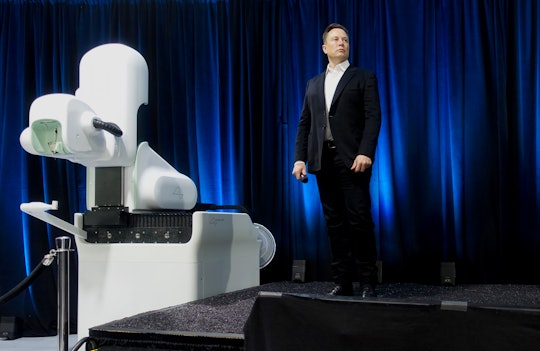 Elon Musk stands on stage next to a Neuralink device