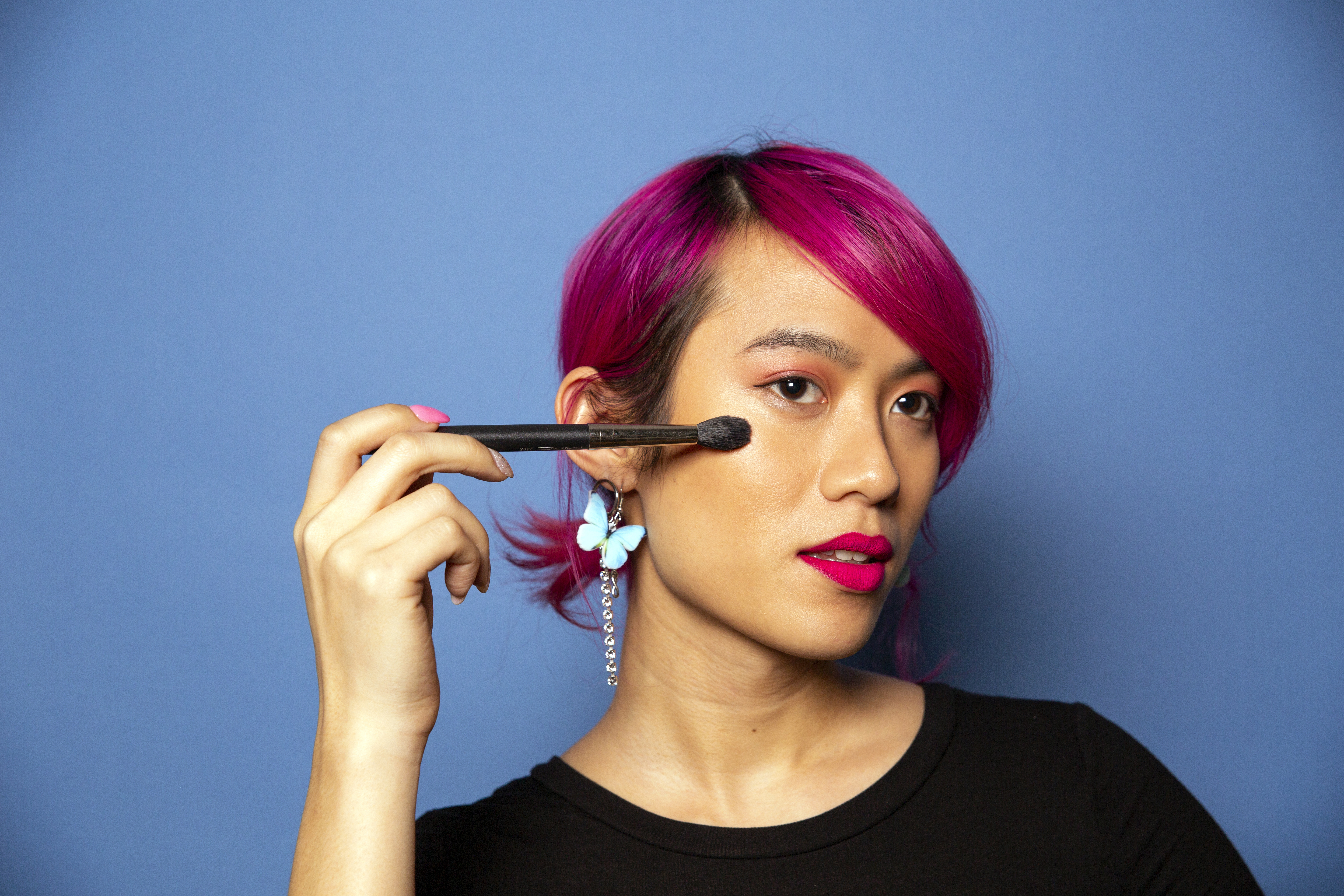 A non-binary femme using a makeup brush