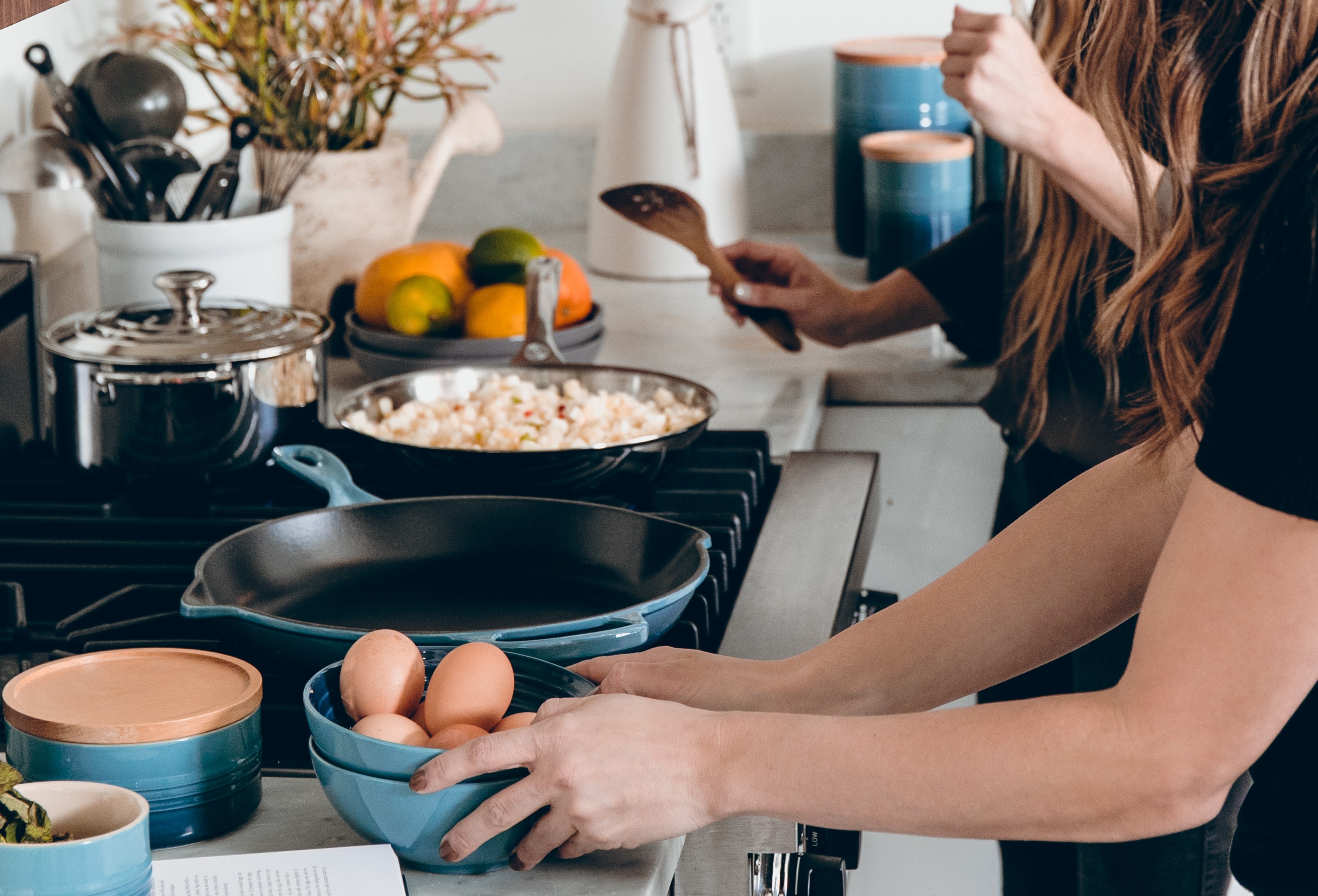 close up of several pans on the stove and a person cooking in one