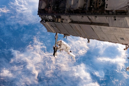 astronaut in space astronaut working on the international space station against a backdrop of clouds