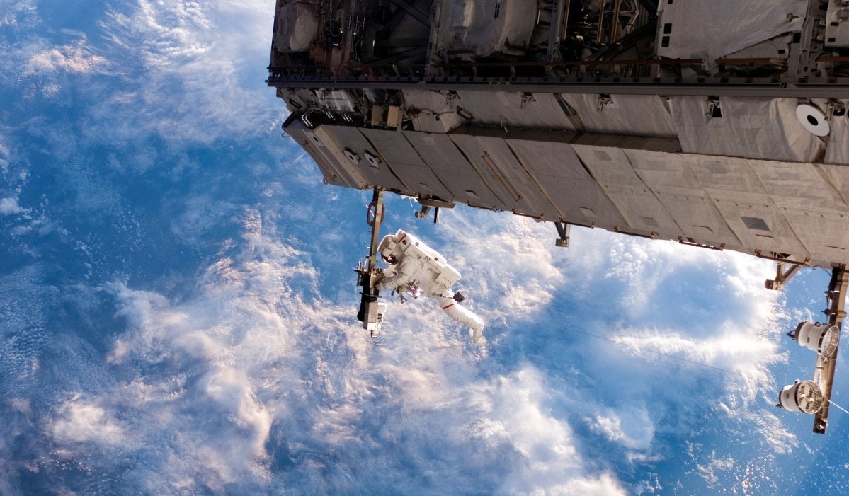 astronaut working on the international space station against a backdrop of clouds