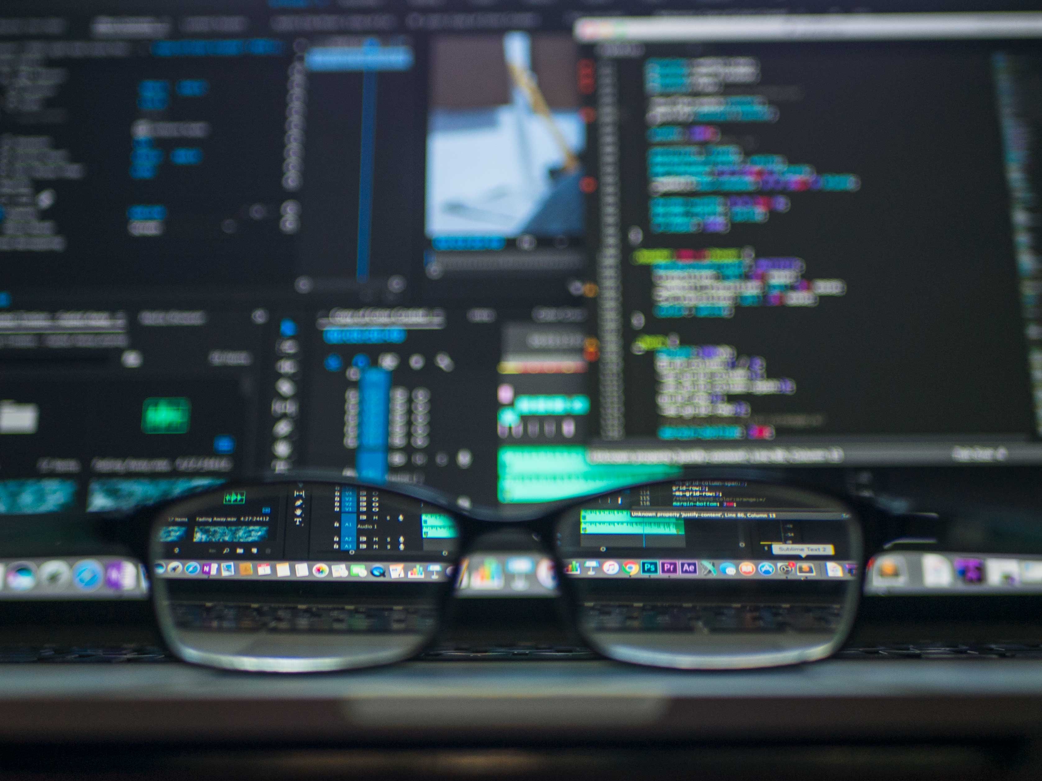 A blurry screen with computer code on it. Looking through the lens of a pair of glasses makes the code easy to read. 