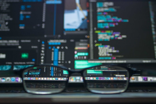 A blurry screen with computer code on it. Looking through the lens of a pair of glasses makes the code easy to read.  A blurry screen with computer code on it. Looking through the lens of a pair of glasses makes the code easy to read.