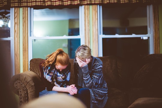Two people sitting on a sofa with their heads in their hands.