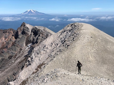 person hiking along the crater of the mountain