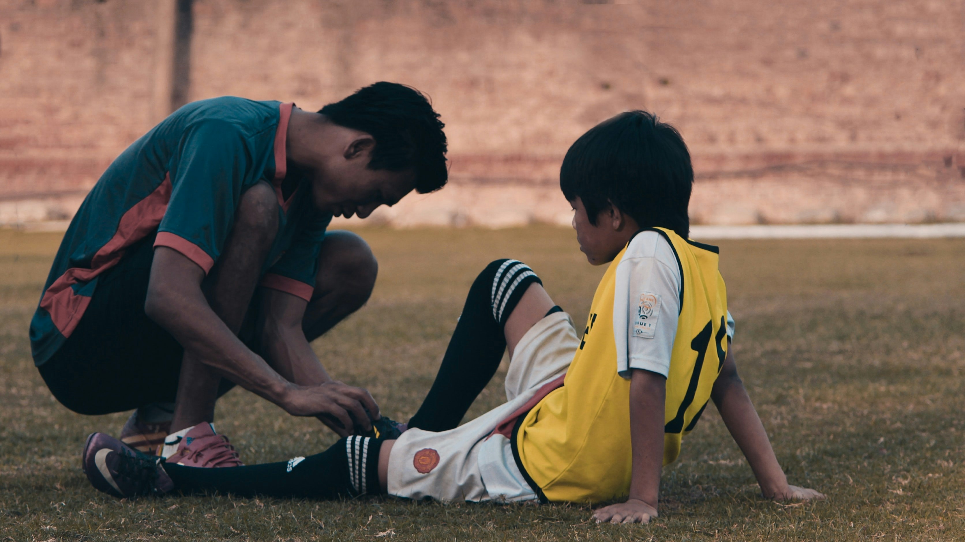 two young soccer players, one with an injury and one helping him