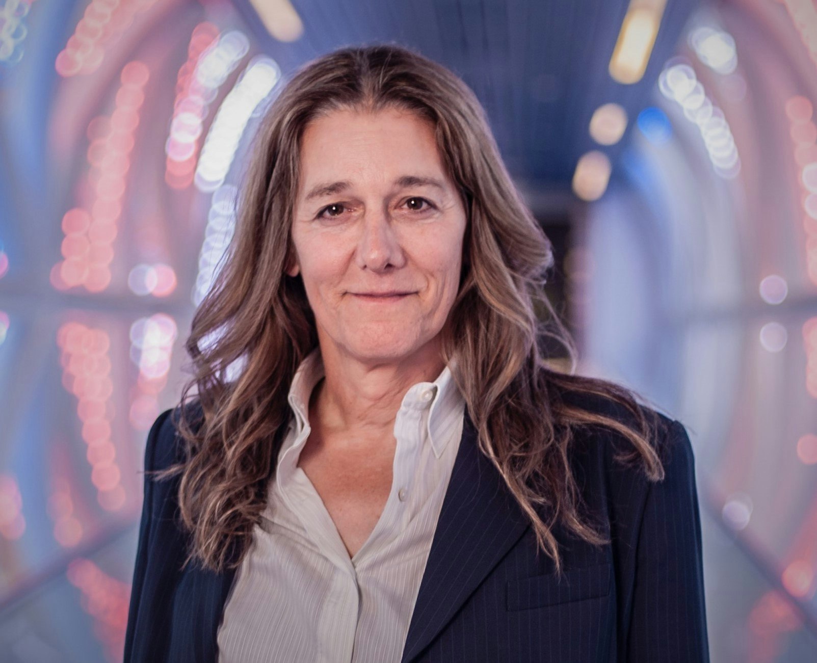 A headshot of Martine Rothblatt, a woman with shoulder-length brown hair, wearing a white shirt and a navy jacket.
