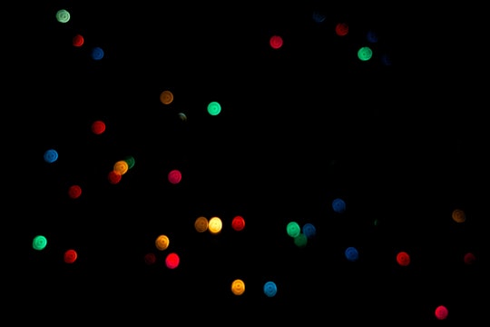 brightly colored green, red, blue, and yellow dots against a black background