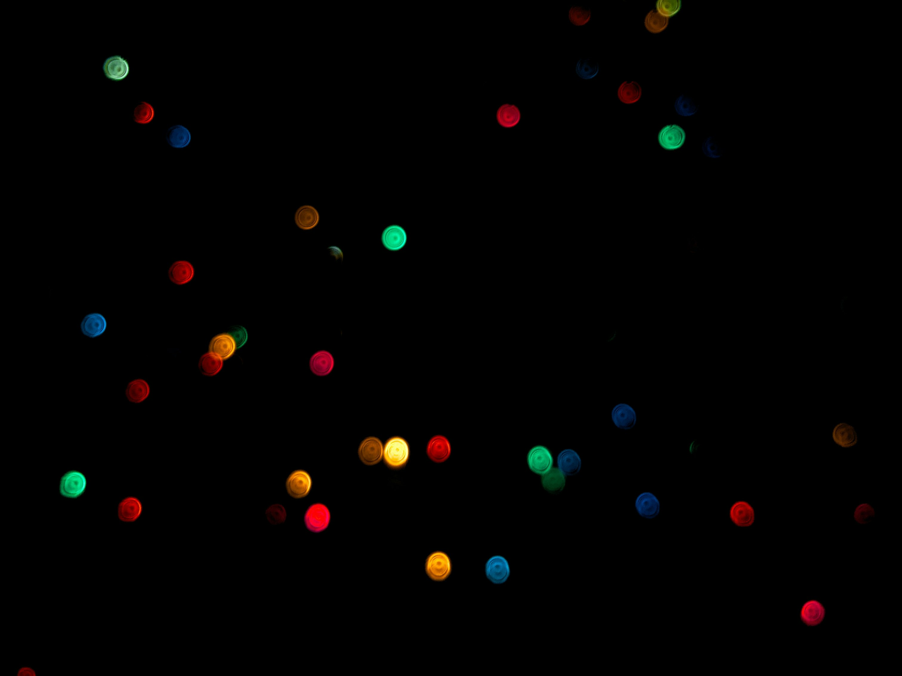 brightly colored green, red, blue, and yellow dots against a black background