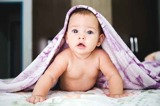 a baby underneath a blanket looking at the camera