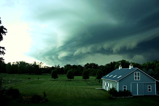 a large cloud over a house and green grass