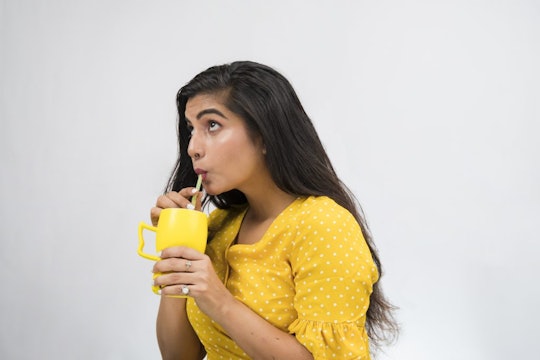 a girl wearing yellow drinking from a yellow cup out of a straw