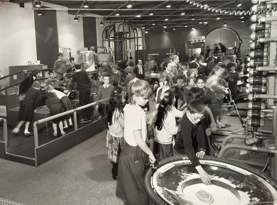 A black and white photo of children in the late 1980s playing with an interactive space exhibit