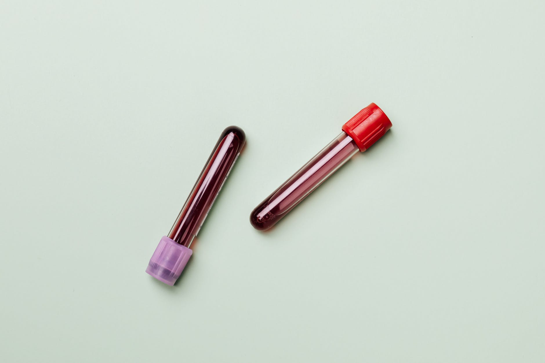 two vials of blood against a pale green background