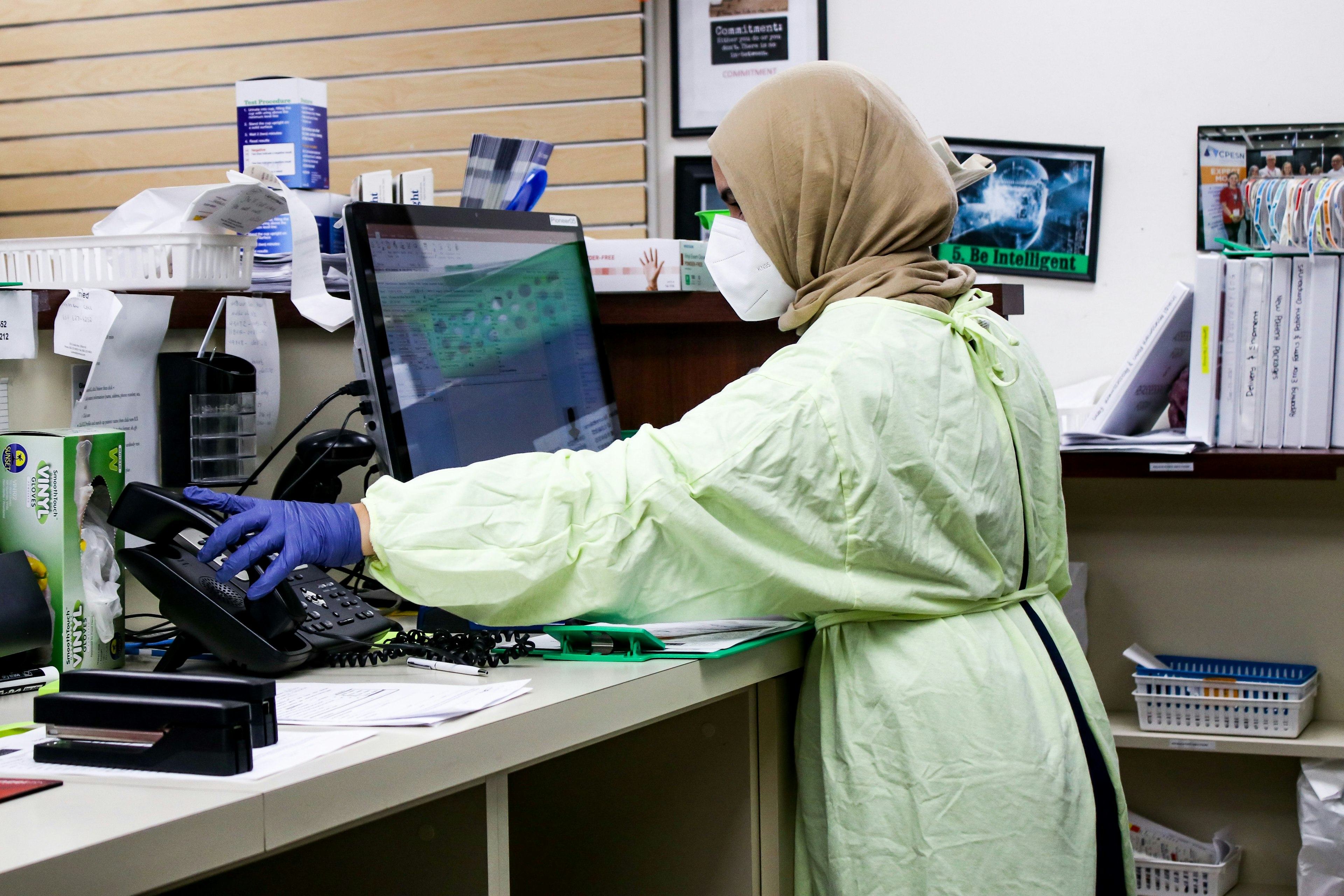 a woman wearing protective gear in a hospital working at a computer