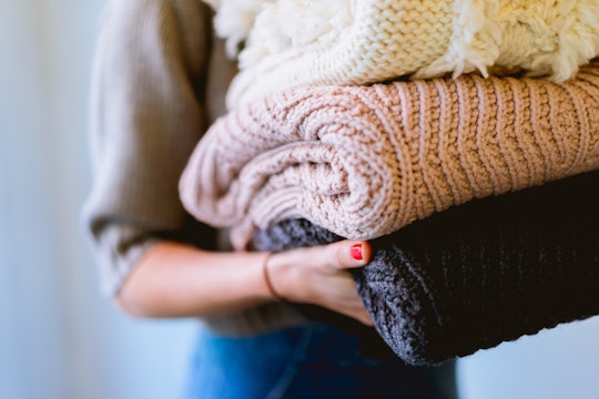 person holding folded sweaters