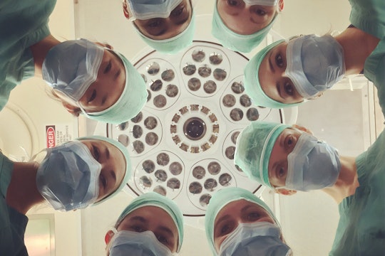 A group of doctors and nurses below surgical lights