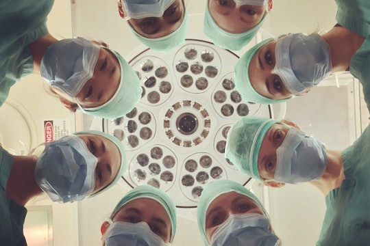 A group of doctors and nurses below surgical lights A group of doctors and nurses below surgical lights