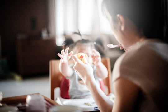 mother feeding child a mother feeding her child sitting in a high chair