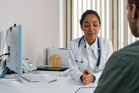 a woman doctor speaks with a man who is only partially visible