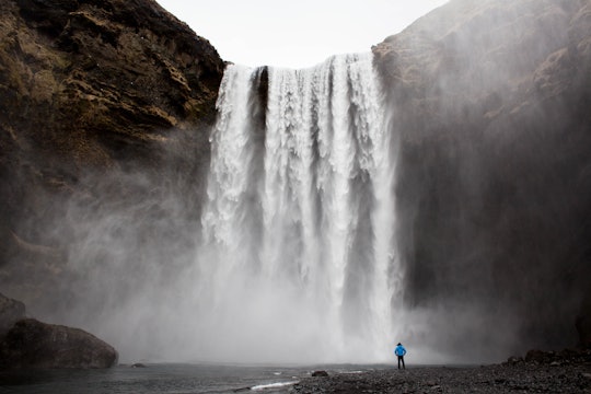 a person standing at the bottom of a huge waterfall